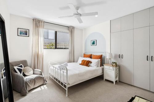 a white bedroom with a bed and a chair at Luxurious Beach House with Breath-taking Views in Ocean Grove