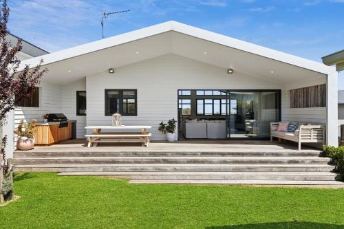 a white house with a bench and a table at Luxurious Beach House with Breath-taking Views in Ocean Grove