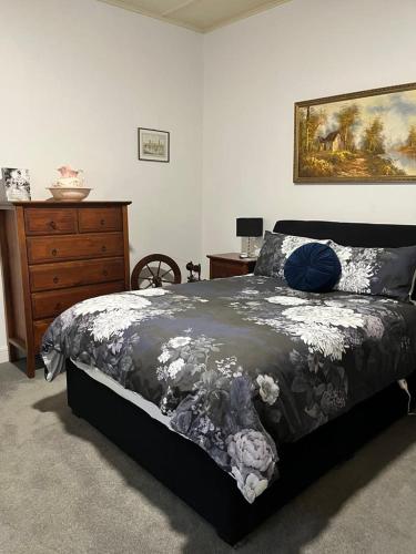 a bedroom with a bed and a dresser and a painting at Copper Mine Cottage in Burra