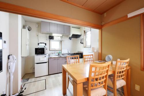 a kitchen with a wooden table and chairs in a room at プレジール弘前101 in Hirosaki