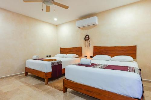 a bedroom with two beds and a fan at Calea Tulum Boutique Hotel in Tulum
