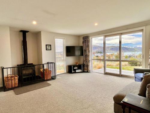 a living room with a tv and a large window at Blae Loch - Lake Tekapo in Lake Tekapo