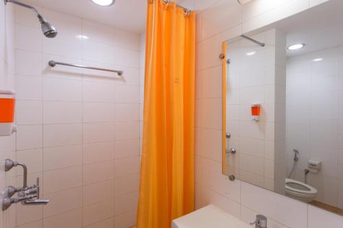 an orange shower curtain in a bathroom with a sink at Ginger Pondicherry in Pondicherry