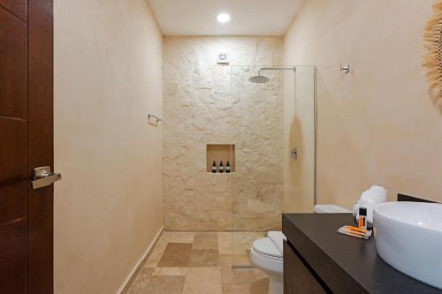 a bathroom with a shower and a toilet and a sink at Calea Tulum Boutique Hotel in Tulum