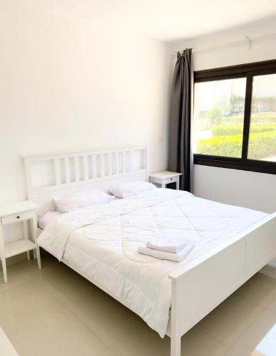 a white bedroom with a white bed and a window at El Gouna -G-cribs B6 in El Gouna