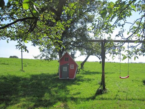 a red house sitting under a tree in a field at Starry sky Comfortable holiday residence in Huf