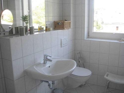 a white bathroom with a sink and a toilet at Poseidon in the Amrumer Welle in Wittdün