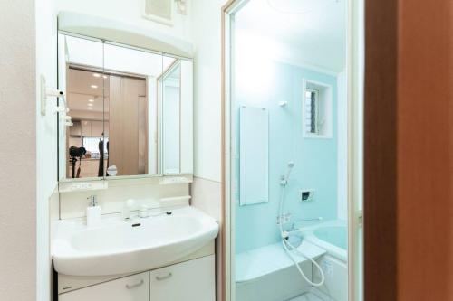 a white bathroom with a sink and a mirror at 天下茶屋vii 忙しい旅行中も ゆったりした時間を過ごせるお部屋 お勧めコーヒーと共に in Osaka