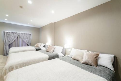 two beds in a room with white walls at 天下茶屋vii 忙しい旅行中も ゆったりした時間を過ごせるお部屋 お勧めコーヒーと共に in Osaka