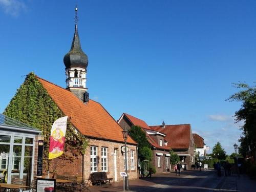 a building with a clock tower on a street at Starfish" Comfortable holiday residence" in Hooksiel