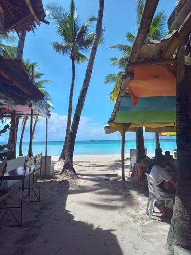 a beach with palm trees and people sitting under umbrellas at MR Holidays Hotel in Boracay