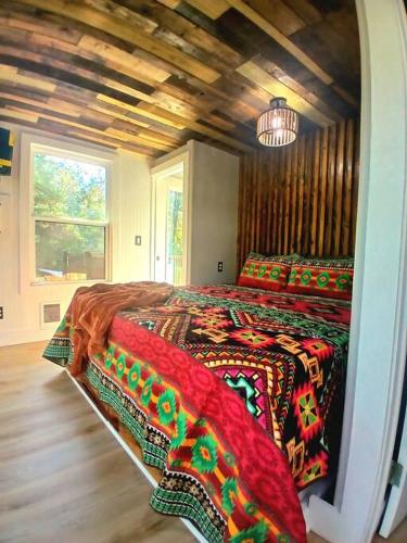 a bedroom with a large bed with colorful blankets at Waterfront Container House In A Magical Forest! in Waller