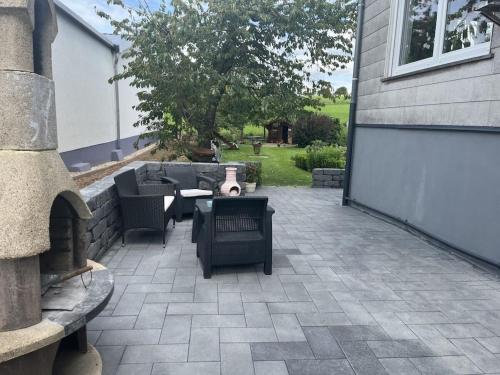 a patio with couches and a fireplace next to a house at Mülli's Ferienwohnung Eifel in Kall