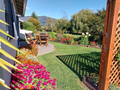 a garden with flowers on the side of a house at Patons Rock Beach Villas in Takaka