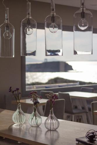 three glass vases sitting on a table with flowers in them at Hotel Grotta in Naxos Chora