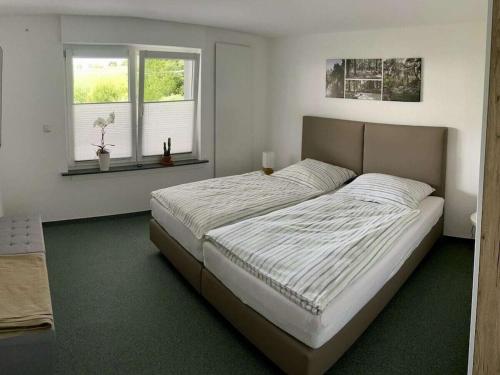 a bedroom with a large bed and two windows at Mülli's Ferienwohnung Eifel in Kall