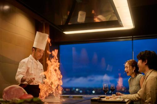 a chef standing in a kitchen with a fire at ANA Crowne Plaza Kanazawa by IHG in Kanazawa