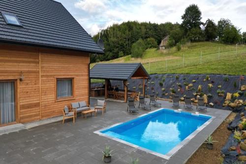 a patio with a pool and chairs and a house at Holiday Home Wi niowa with Pool and Mountain Views in Iwierzyce