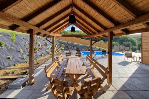 a wooden table and chairs under a wooden roof at Holiday Home Wi niowa with Pool and Mountain Views in Iwierzyce