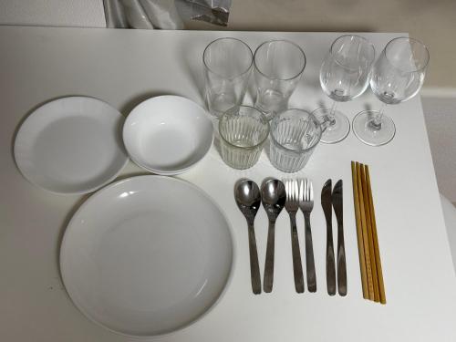 a table with plates and wine glasses and utensils at Town Court Hosoda in Tokyo