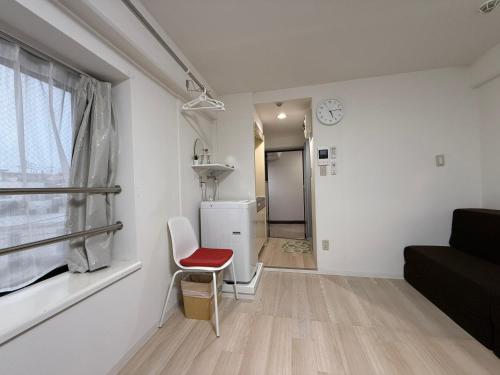 a white living room with a red chair and a window at Town Court Hosoda in Tokyo