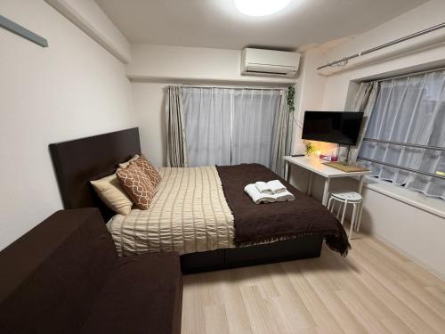 a bedroom with a bed and a desk and a television at Town Court Hosoda in Tokyo