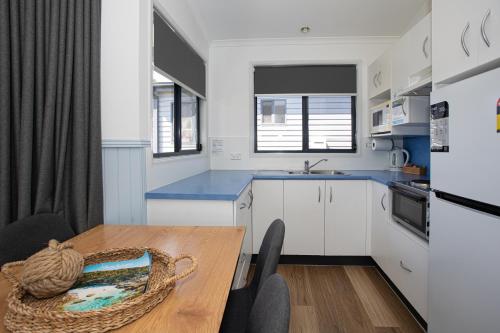 a kitchen with white cabinets and a wooden table at South Coast Retreat in Greenwell Point