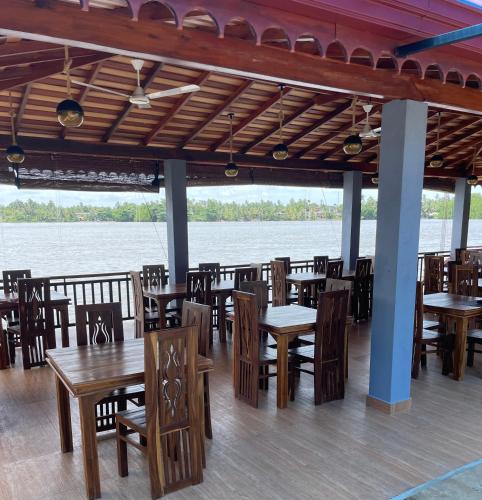 a restaurant with wooden tables and chairs next to the water at Aqua Hotel in Aluthgama