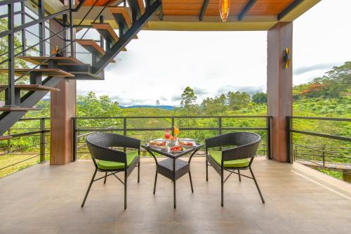a dining room with a table and chairs on a balcony at La Casa Lindula Villa Ceylon in Lindula
