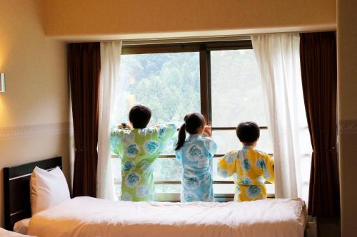 three children in kimonos looking out of a window at Hotel Angel Grandia Echigo Nakazato in Yuzawa