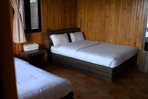 two beds in a room with wooden walls and wooden floors at Srijana Farm in Pālpā