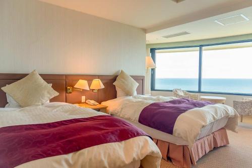 two beds in a room with a view of the ocean at Onahama Ocean Hotel & Golf Club in Iwaki