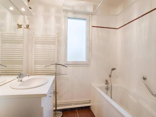 La salle de bains blanche est pourvue d'un lavabo et d'une baignoire. dans l'établissement Appartement spacieux 70m², piscine, parking, près plage et commerces - FR-1-788-38, à Merville-Franceville-Plage