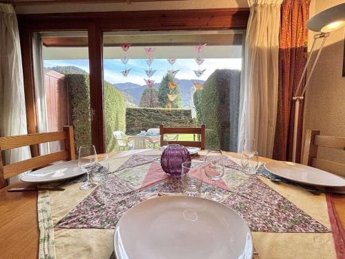 - une table à manger avec des verres à vin et une fenêtre dans l'établissement Studio cabine cosy avec jardin privatif à Praz-Sur-Arly - FR-1-603-110, à Praz-sur-Arly