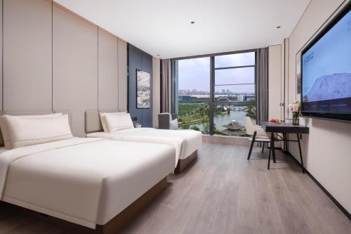 duas camas num quarto de hotel com uma televisão de ecrã plano em Atour Hotel Wuxi Huishan High-Speed Railway Station em Wuxi