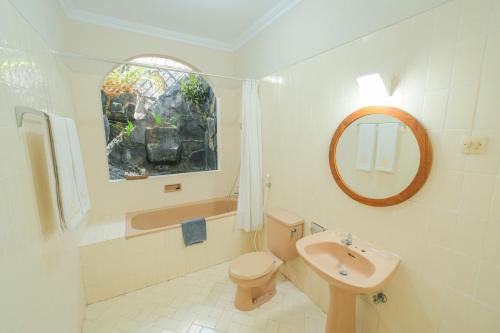 a bathroom with a toilet and a sink and a mirror at Royal Brongto Hotel in Timuran