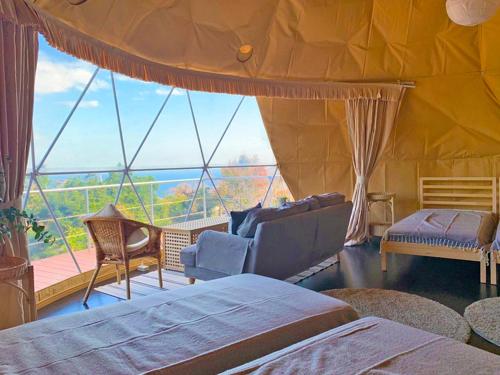 a room with two beds and a large window at 伊豆Cocoグランピングリゾート in Ito
