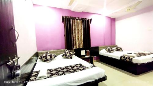 two beds in a room with purple walls at Sai Balaji Residency in Shirdi