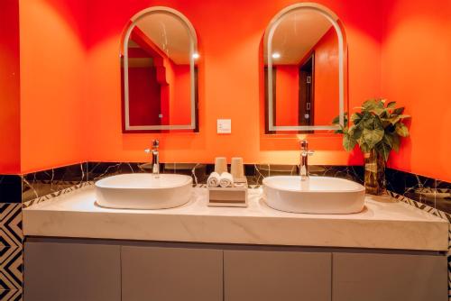 two sinks in a bathroom with orange walls and mirrors at Sapa Hai Yen Hotel and Apartment in Sa Pả