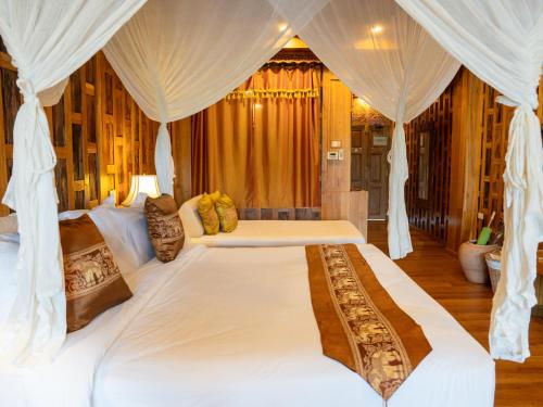 a bedroom with a large white bed with curtains at Santhiya Koh Chang Resort in Ko Chang