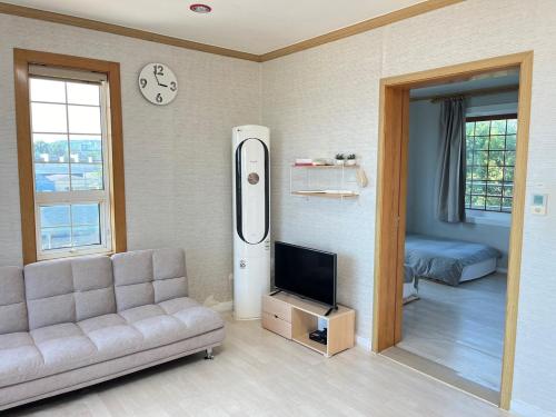 a living room with a couch and a refrigerator at Rom House in Seogwipo