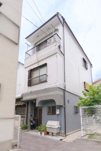 a white building with two balconies on top of it at 易居の宿 in Osaka