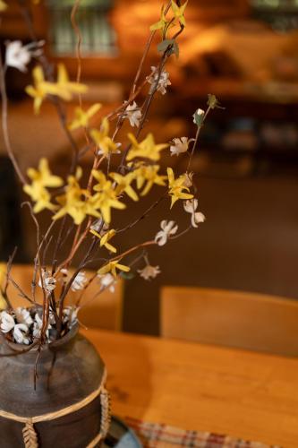 a vase filled with yellow and white flowers on a table at Multi-Level Forest Lodge Near Silverwood with Vintage Ice Cream Parlor & Movie Theater in Spirit Lake