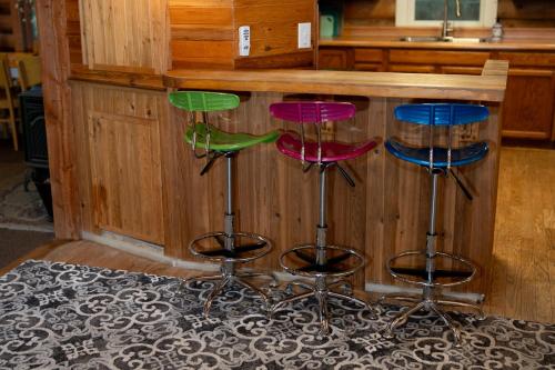 four colorful bar stools in front of a counter at Multi-Level Forest Lodge Near Silverwood with Vintage Ice Cream Parlor & Movie Theater in Spirit Lake