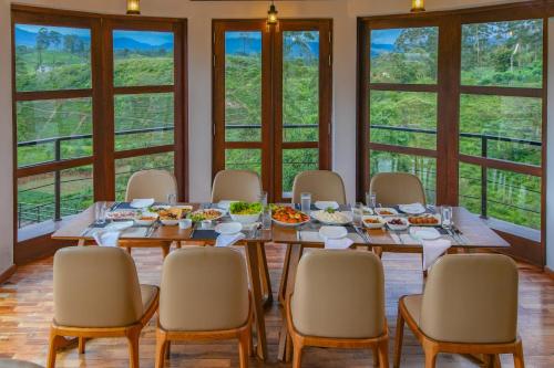 a dining room with a table and chairs and windows at La Casa Lindula Villa Sarendip in Nuwara Eliya