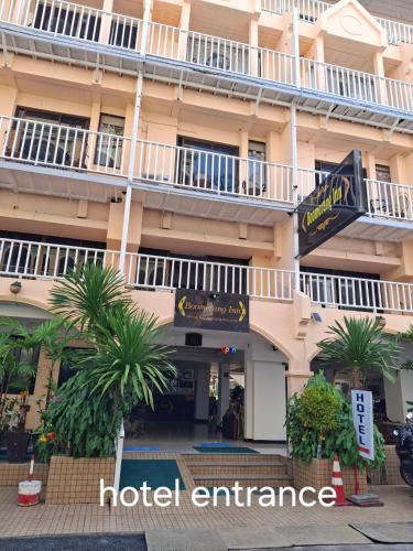 a hotel entrance with palm trees in front of it at Boomerang Inn in Patong Beach