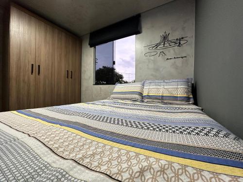 a large bed in a bedroom with a window at Apê térreo sem escada com Ar Cond, WiFi e banheira! in Brasilia