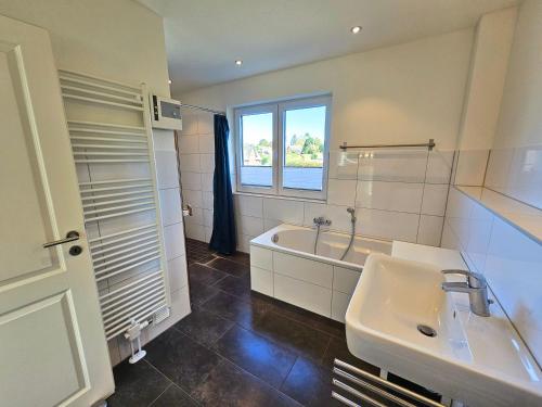 uma casa de banho com um lavatório, uma banheira e uma janela em Sechendorf Ferienhaus Solängen Sechendorf em Blekendorf