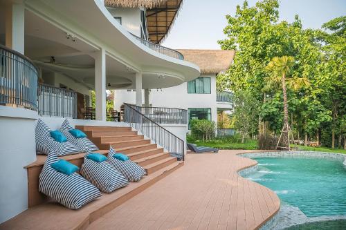 a patio with blue and white pillows next to a swimming pool at Villa De Leaf River Kaeng Krachan in Phetchaburi