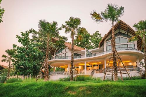 a large house with palm trees in front of it at Villa De Leaf River Kaeng Krachan in Phetchaburi